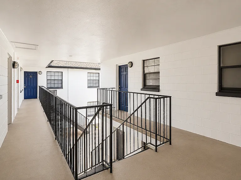 Modern apartment entrance featuring a sleek black door labeled G17, with stylish windows and elegant railing in a clean white hallway.