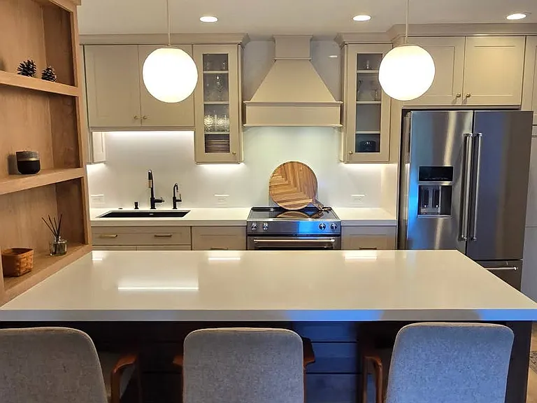 Large center island with white quartz counter top, custom oak shelving and counter-height seating for 3, stylish white glass globe pendent lights