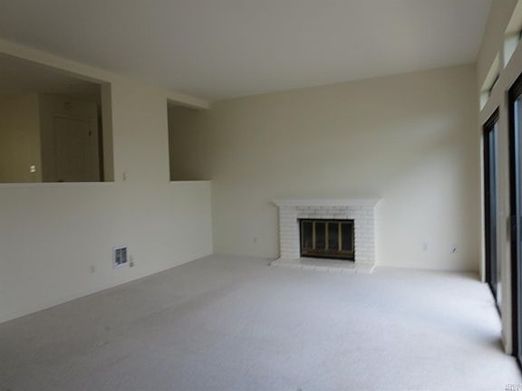 Large living room with built-in bookshelves, fireplace and sliding doors to view deck