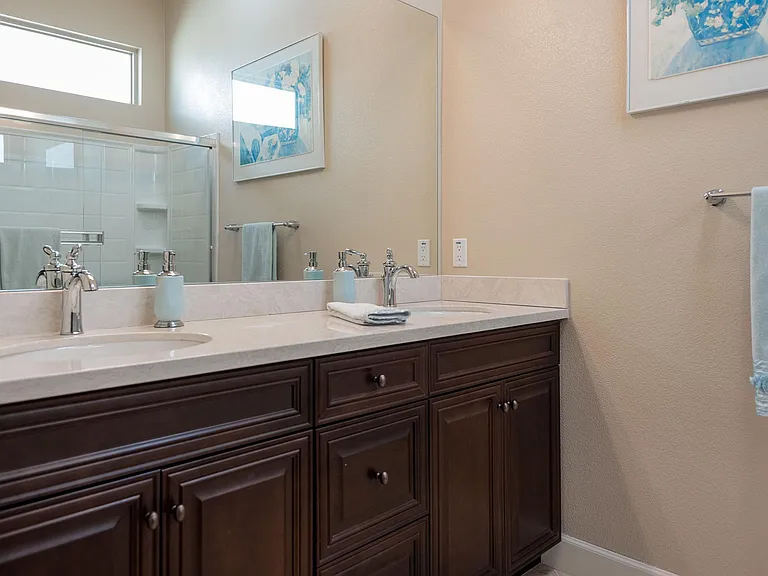 En suite guest bathroom with shower over tub, double vanities, separate water & wardrobe closets.