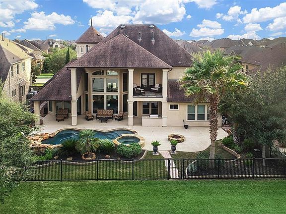 View of the backyard oasis - tons of space to entertain outside under the large covered patio, upstairs balcony or out on the pool deck. Notice the outdoor kitchen, firepit and of course, hot tub & pool!