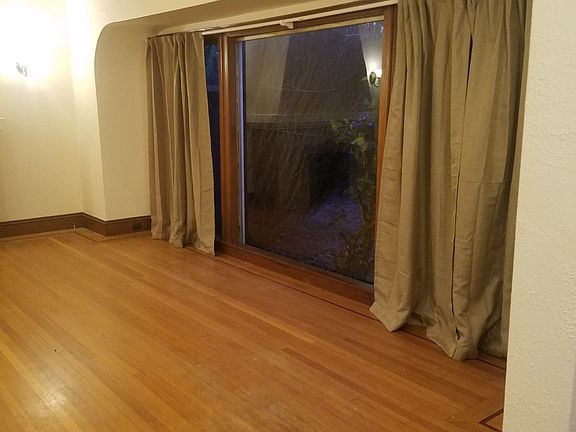 The living room with a full length window and hardwood floor