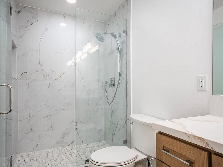 Newly remodeled primary bathroom with large-scale porcelain tile walk-in shower and luxury Hansgrohe shower system.