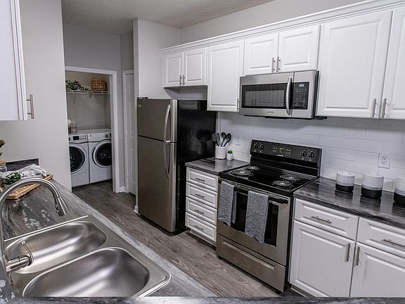 Experience timeless elegance in our updated kitchens, featuring white cabinetry, a modern subway tile backsplash, and wood-style flooring with stainless-steel appliances.