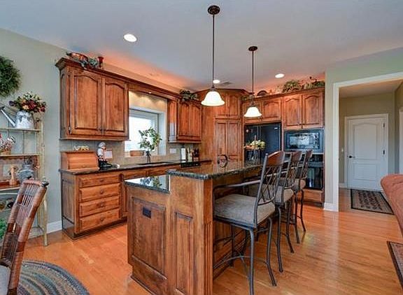 Kitchen offers granite counters, tile back splash, walk in pantry, wood floors and lower cabinets with pull out drawers.