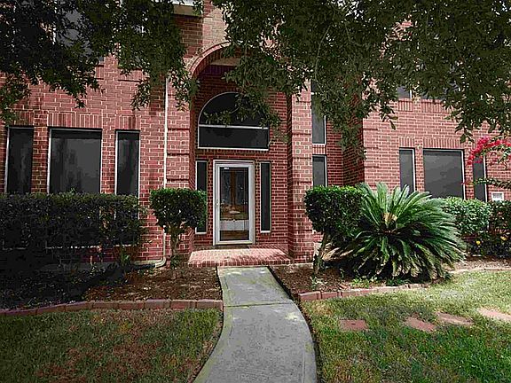 Covered entry with lush landscaping.