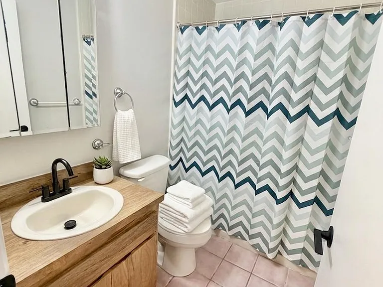 Full bathroom with a single-sink vanity, mirrored medicine cabinet, and tub/shower combo with curtain and tile surround.