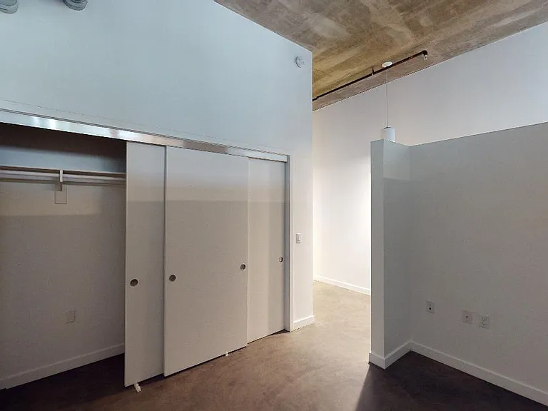 Spacious apartment bedroom with polished concrete flooring.