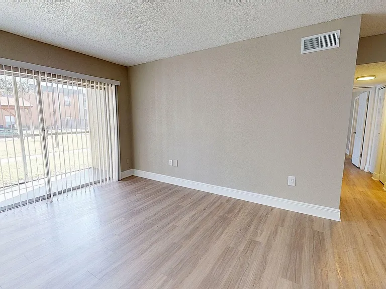 Bright and inviting living room with large sliding glass doors and elegant wood flooring, offering a seamless indoor-outdoor flow.