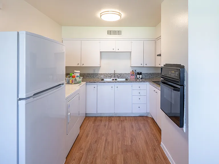 Kitchen with granite countertop, glass cooktop, built-in oven, washer/dryer and refrigerator.