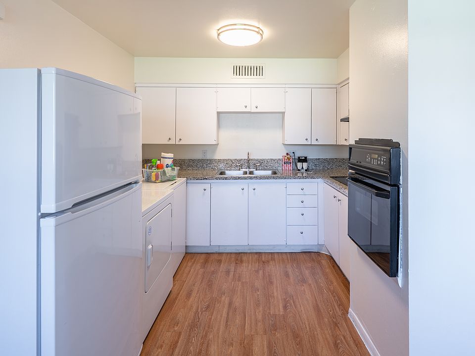 Kitchen with granite countertop, glass cooktop, built-in oven, washer/dryer and refrigerator.