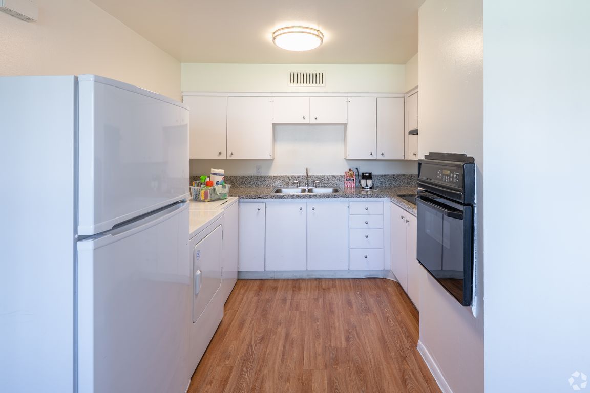 Kitchen with granite countertop, glass cooktop, built-in oven, washer/dryer and refrigerator.