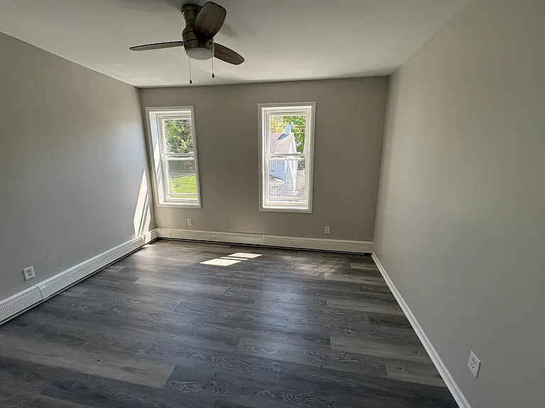 Large bedroom with ceiling fan in the front of the apartment