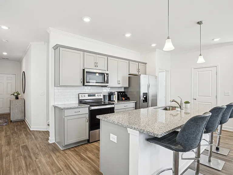 View of the kitchen and entry hallway. Offering bar seating, plenty of cabinet space and granite countertops.