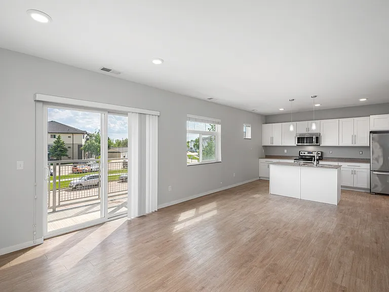 Bright, spacious open-concept living area with modern kitchen, large windows, and sliding glass doors leading to a balcony. Bright, spacious open-concept living area with modern kitchen, large windows, and sliding glass doors leading to a balcony.