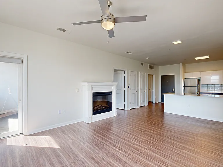 Apartment kitchen with stainless steel appliances, dining and living room with wood-style flooring.