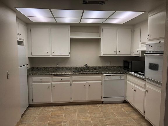 Large kitchen with lots of cabinets, granite countertops, large double stainless steel sink & faucet, refrigerator, microwave oven, oven and dishwasher.