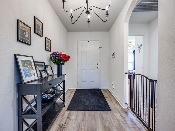 Entrance foyer with light wood-type flooring, arched walkways, a chandelier, and a textured wall