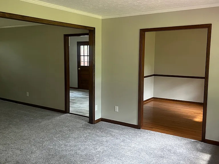 Front door view of dining room (hardwood floors) and kitchen entrance.