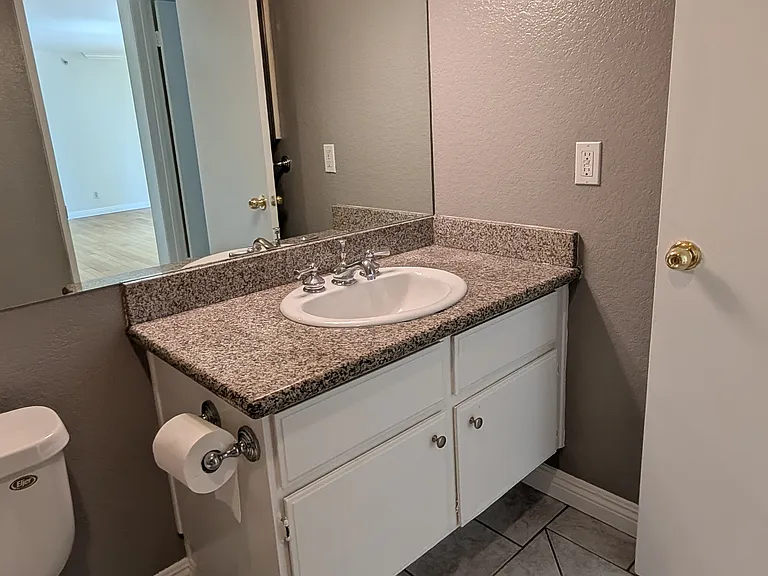Second bathroom vanity with mirror, tile flooring, and neutral finishes.