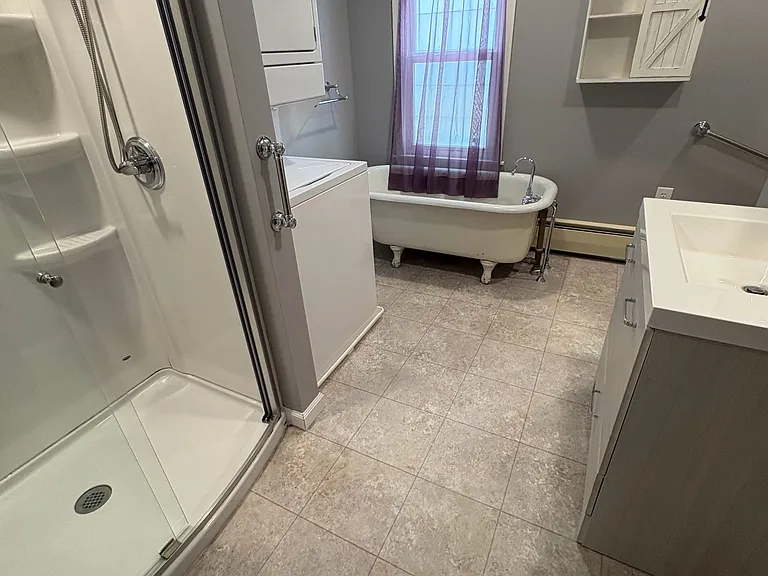 Bathroom with walk in shower and soak tub. Washer and dryer combo unit.