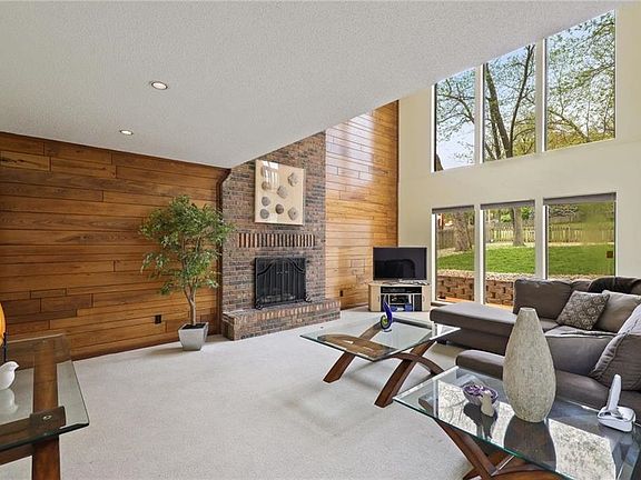 The living room really makes an impression with the vaulted ceilings, wall of windows, and two-story brick fireplace.
