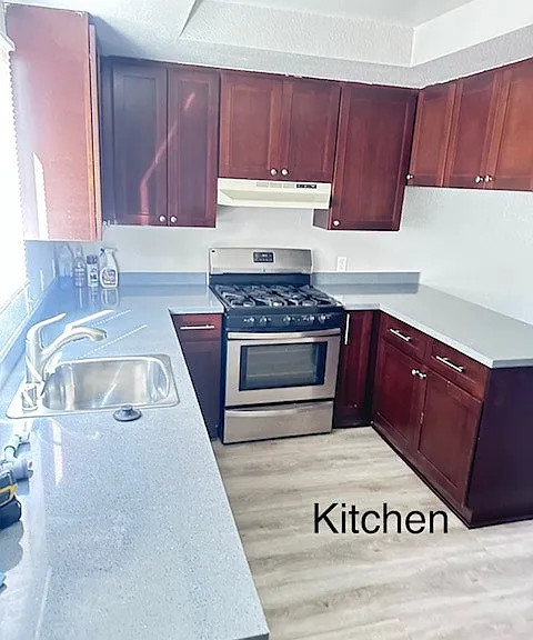 "Kitchen featuring gas stove and dual sink."