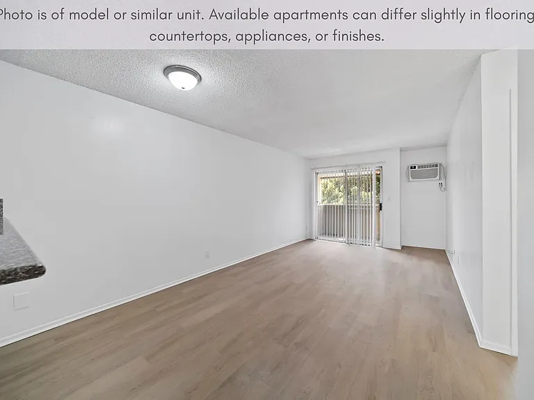 Open living space with modern flooring and sliding glass doors leading to balcony.