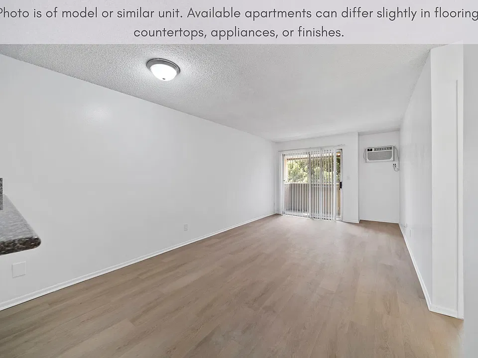 Open living space with modern flooring and sliding glass doors leading to balcony.