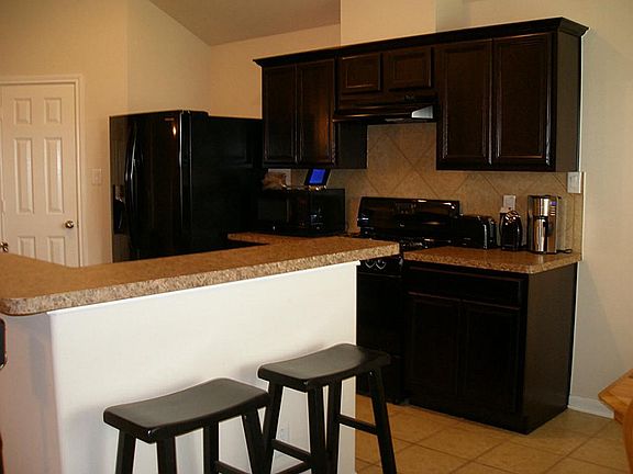 WHAT A STUNNING KITCHEN WITH BEAUTIFUL DARK CHERRY WOOD CABINETS WITH BLACK GAS STOVE & DISHWASHER