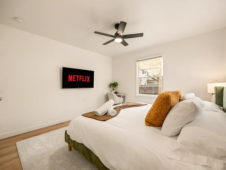Spacious primary bedroom featuring a king bed, dedicated workspace, ceiling fan, and a calm, relaxing atmosphere ideal for extended stays or working remotely.