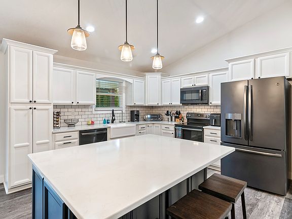 Large kitchen with island/bar, quartz countertops, black stainless appliances and farmhouse sink
