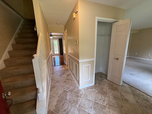 Front entrance looking up stairs, down hallway to kitchenette and back deck, and living room to the right