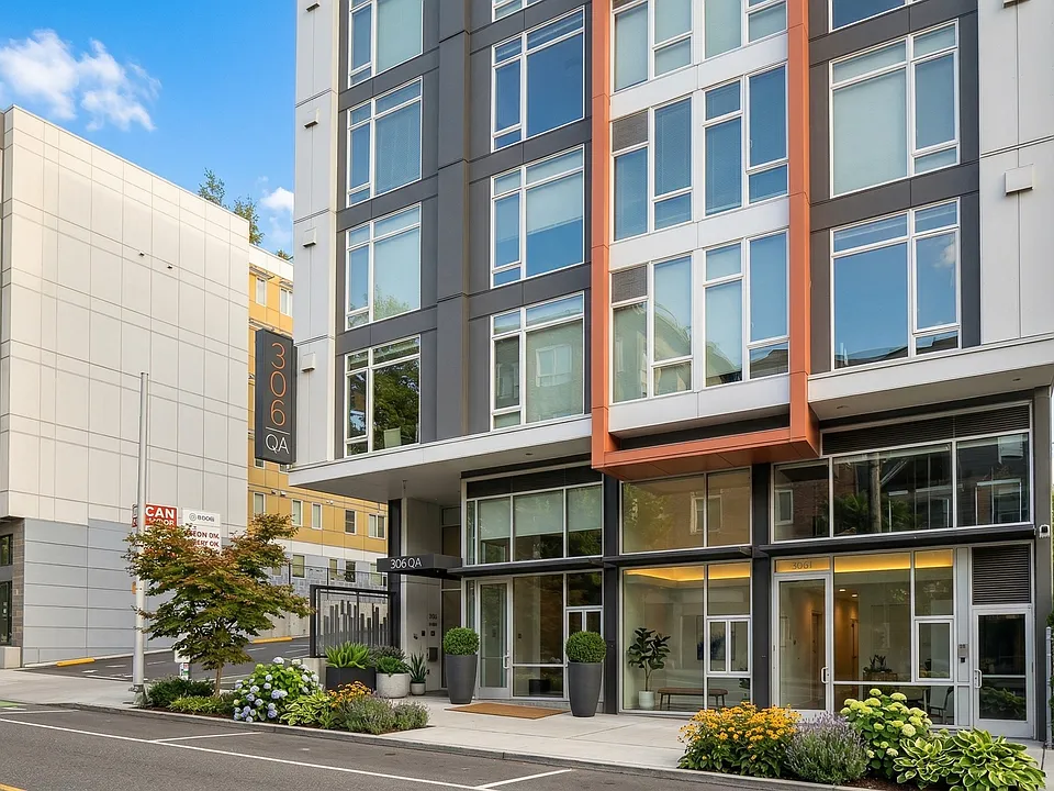 Street-level view of 306 Queen Anne in Seattle showing the main entrance, glass lobby frontage, and landscaped sidewalk planters.