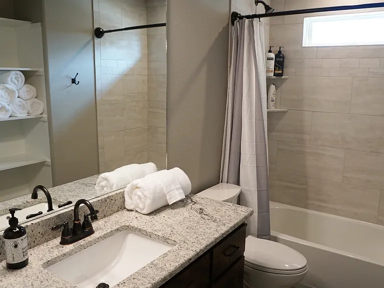 The master bathroom features a shower/tub combo, granite-topped vanity, bronze fixtures, and built-in storage for towels and essentials all attached to a huge walk-in closet.