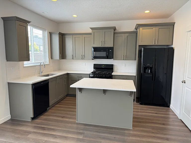 Kitchen with new microwave oven, dishwasher, side-by-side refrigerator, gas range, island and quartz countertop.