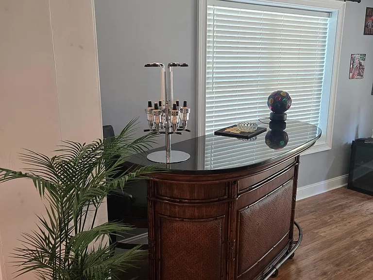 Common lounge area with a built-in bar counter, seating, and a large window with blinds for privacy and daylight.