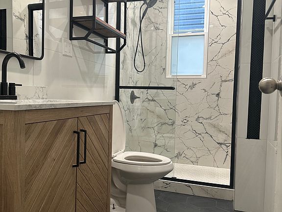 Vanity with ample storage space and large medicine cabinet above. Shelving unit and towel racks.