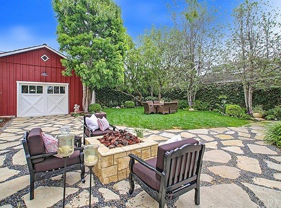 Large back yard with multiple seating options. Access to red garage via driveway and alley.