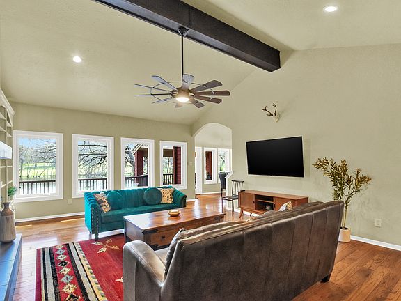 Open concept living room with 2 couches, fireplace and large flat screen TV with natural light.