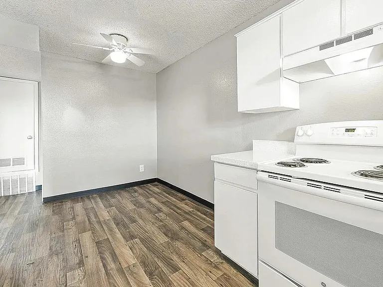 Bright and inviting kitchen with sleek white cabinetry, modern appliances, and elegant wood flooring.