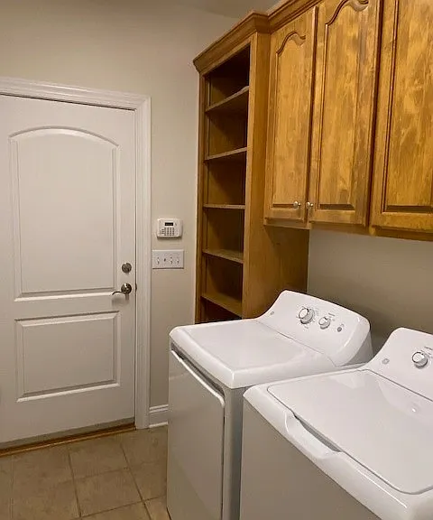 Laundry room with built in cabinets and storage closet