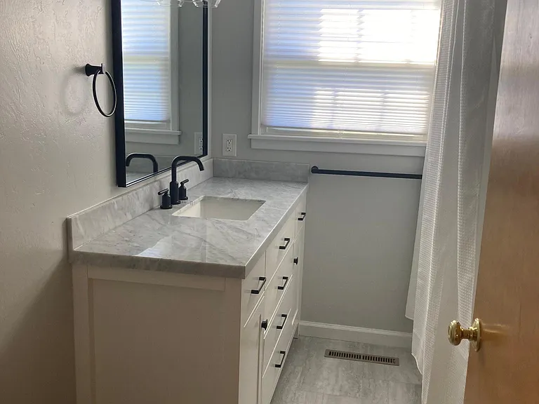 Bathroom - completely remodeled with new bathtub, tile, vanity, lighting, mirror, window covering, and fixtures.