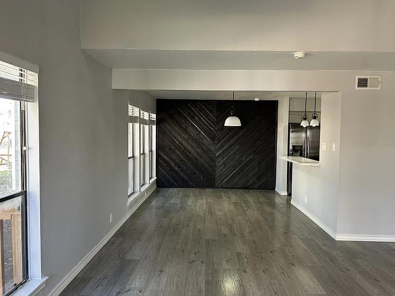 Connected to the living area is the dining area, complete with a black painted wooden wall and a breakfast bar.