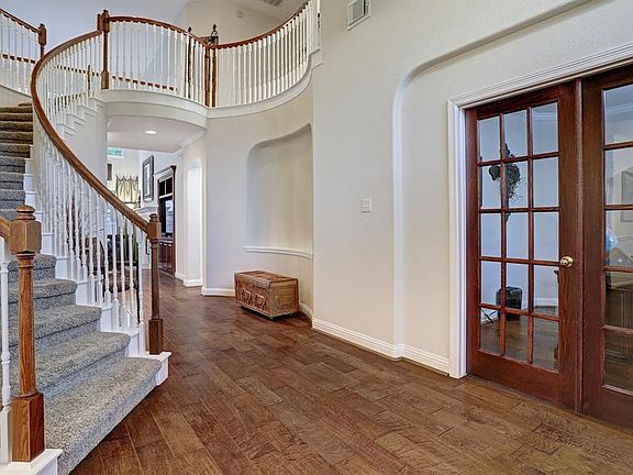 View from the entrance, notice the sweeping staircase and curved walls with alcove. Gorgeous hardwood flooring continues through the main rooms of the 1st floor. Formal office on the right through the french doors.