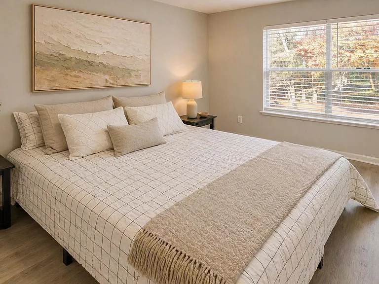 Well-appointed bedroom with a large window, neutral finishes, and space for nightstands and additional storage.