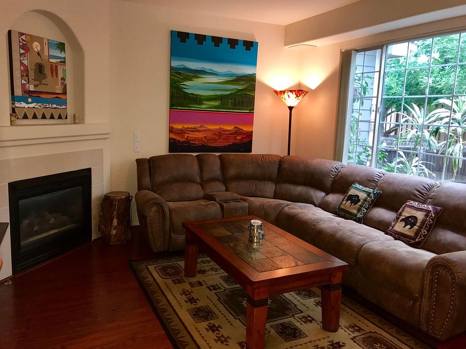 Living room with gas fireplace and window with view of back patio and open space/dog park beyond it.