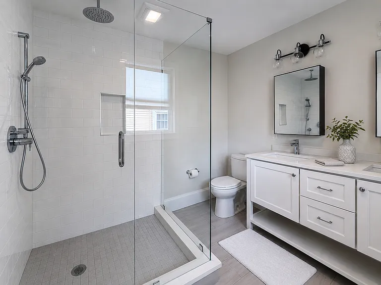 Modern primary bathroom with spacious walk-in glass shower, two sinks and clean contemporary finishes