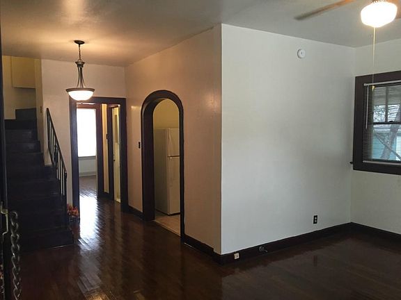 View of living room, kitchen, primary bedroom, and stairs leading upstairs