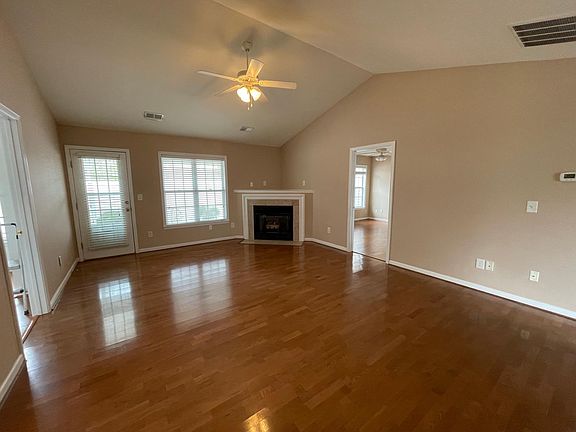 Living Room with laminate wood flooring throughout, cathedral ceiling, fireplace, and ceiling fan.